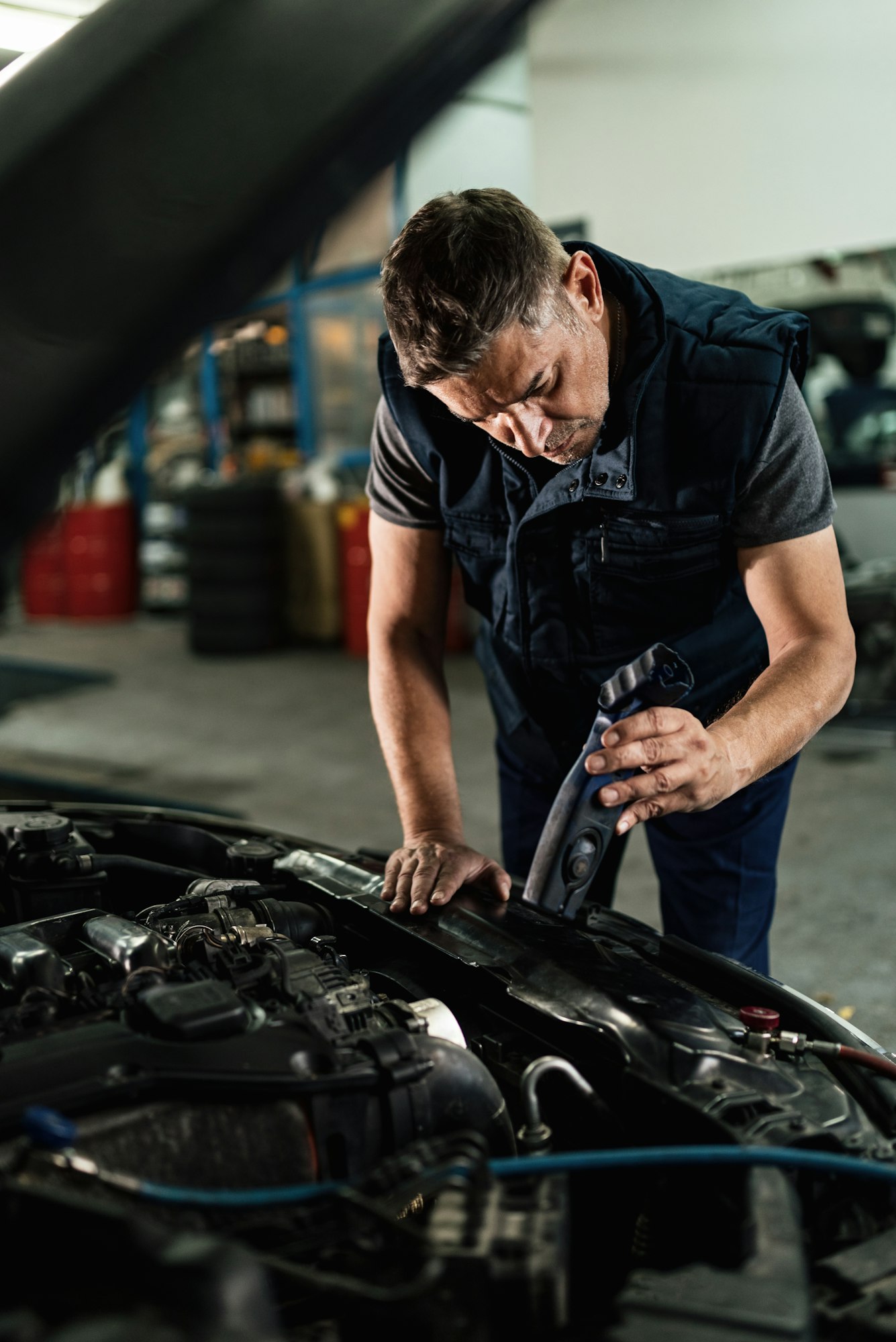Mechanic examining car engine in auto repair shop.